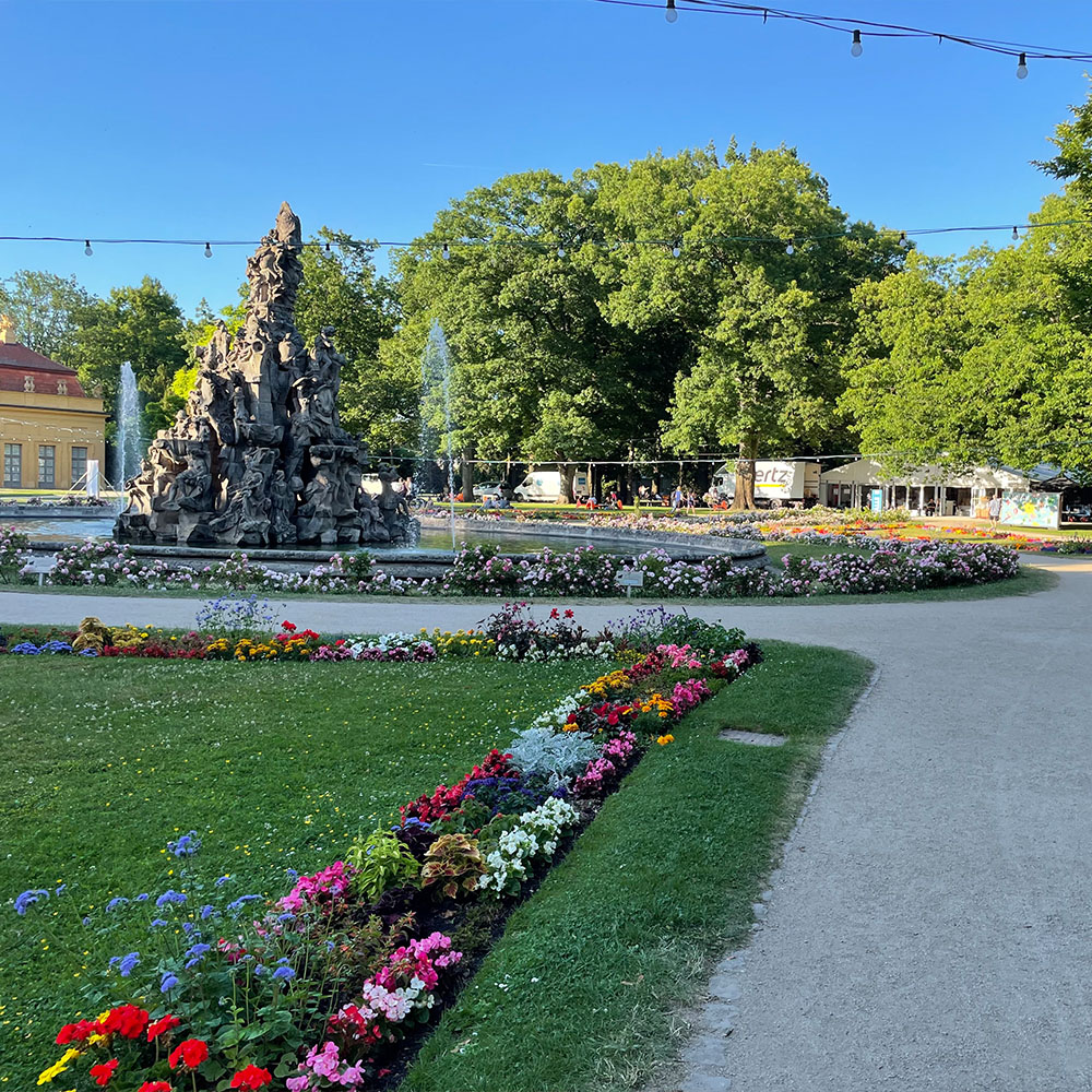 Blick in den Schlossgarten von Erlangen mit Brunnen und Blumenrabatten.